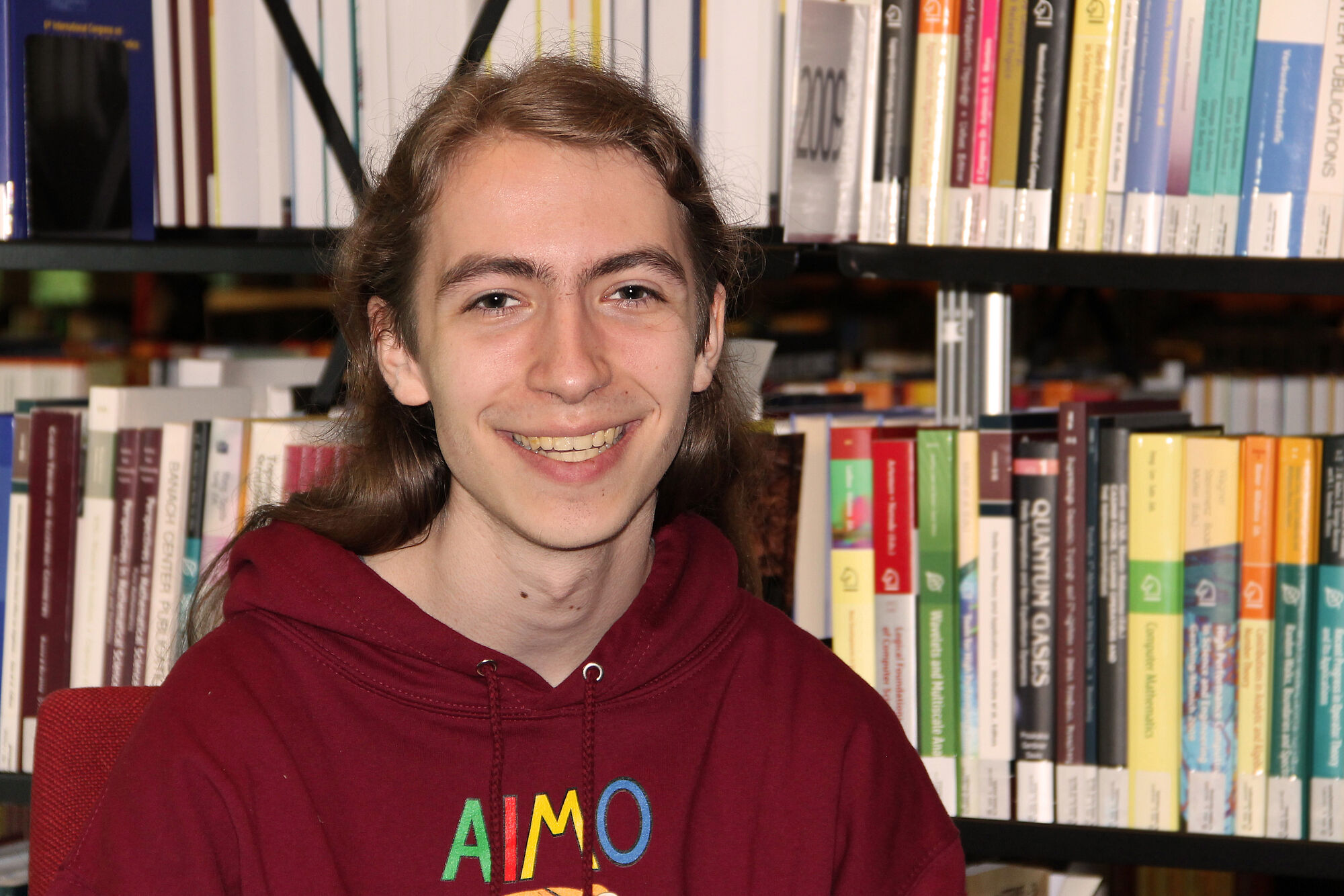 Johannes Raitz von Frentz mit IMO 2024-Pullover vor einem Bücherregal