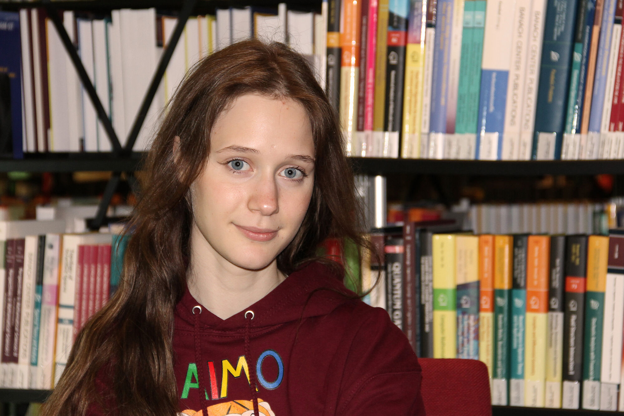 Vera Lavrova mit IMO 2024-Pullover vor einem Bücherregal