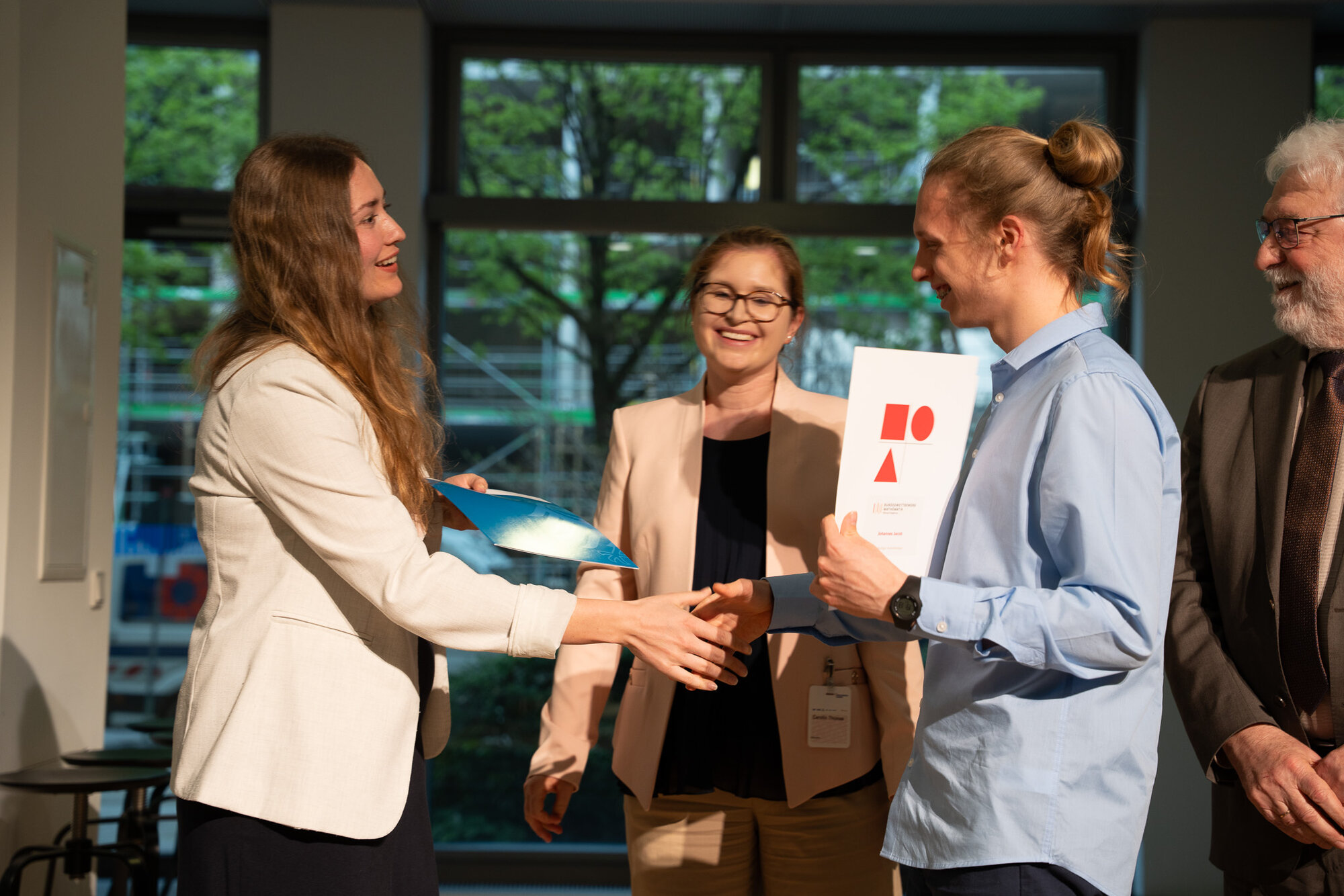 Preisträger bekommt Urkunde überreicht mit Händeschütteln