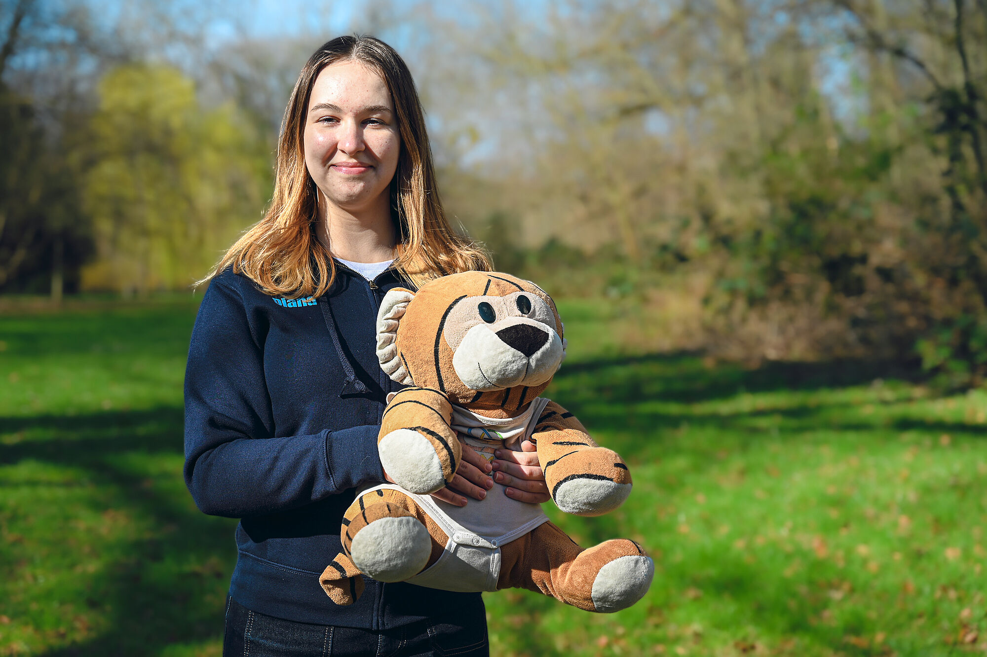 Diana Reznychenko mit MathemaTigerin und EGMO-Pullover im Grünen. 