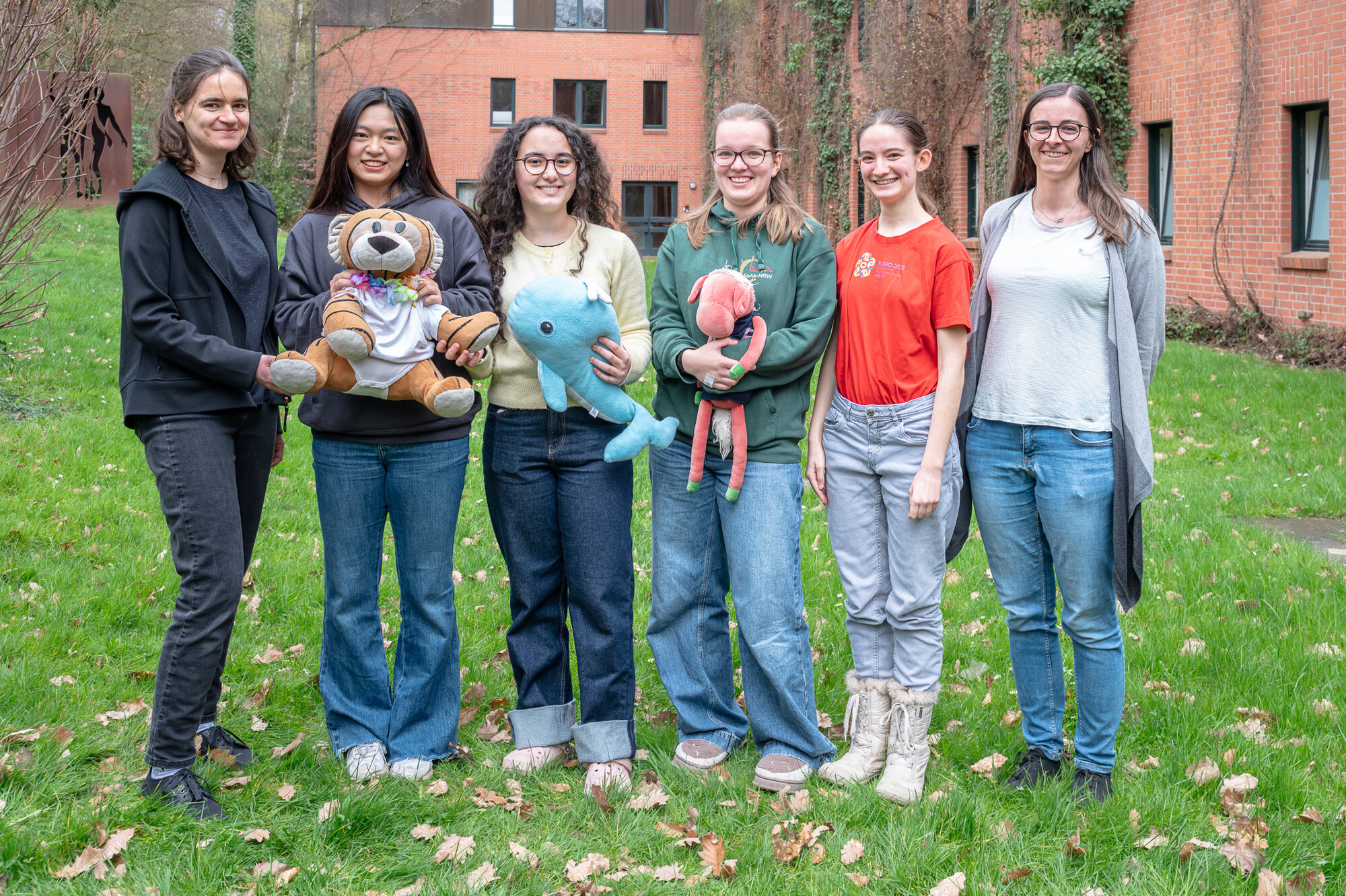 Vier junge Mädchen und ihre Betreuerinnen stehen auf einer Wiese