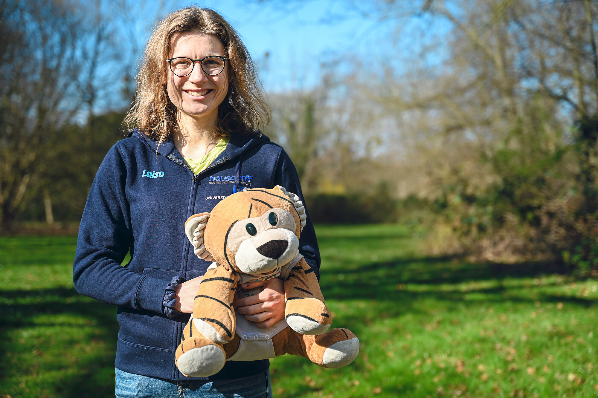 Luise Puhlmann mit MathemaTigerin und EGMO-Pullover im Grünen. 