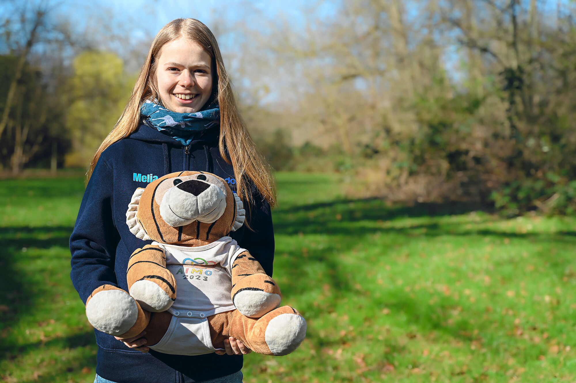 Melia Haase mit MathemaTigerin und EGMO-Pullover im Grünen. 