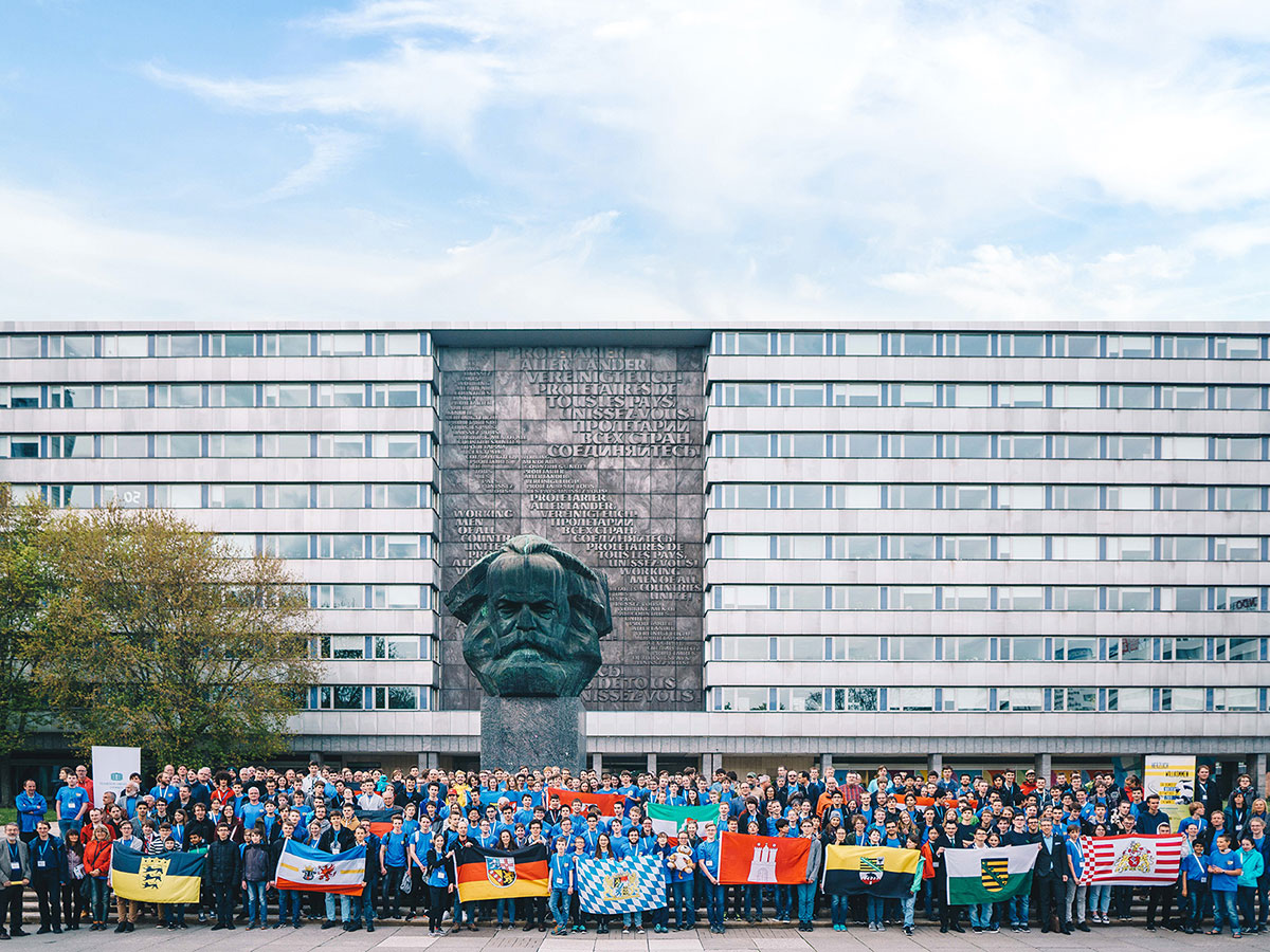 Teilnehmende der Mathematik-Olympiade stehen vor Karl-Marx-Monument in Chemnitz.