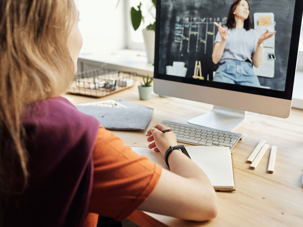 Mädchen sitzt vor einem Laptop und schaut sich ein Video an.