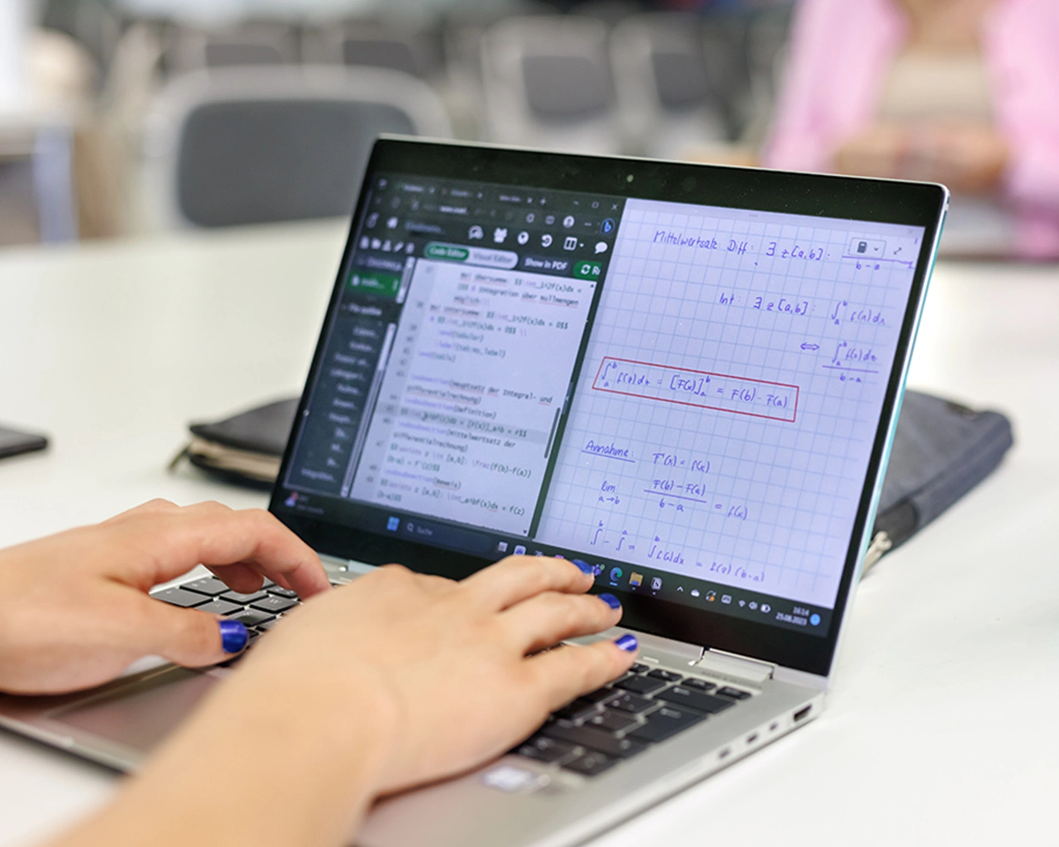 Ein Laptop mit mathematischen Zeichen, tippende Hände auf der Tastatur